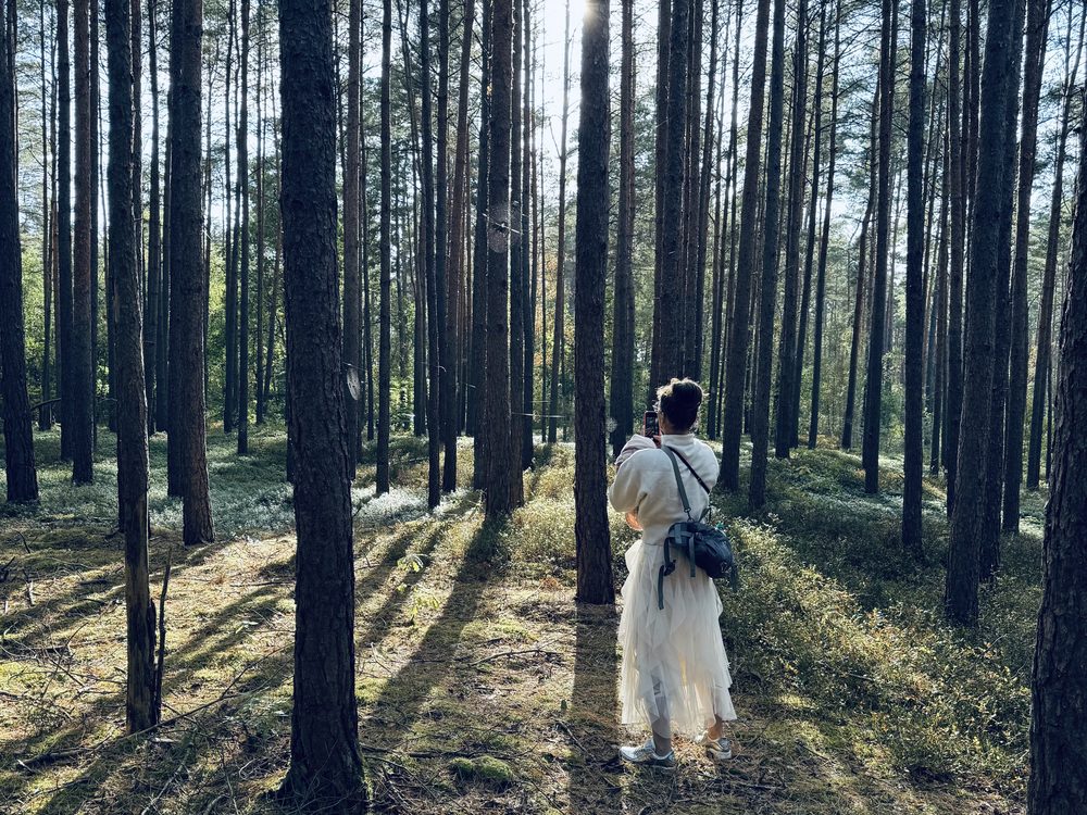 Franziska von Bredow steht in einem lichtdurchfluteten Kiefernwald
